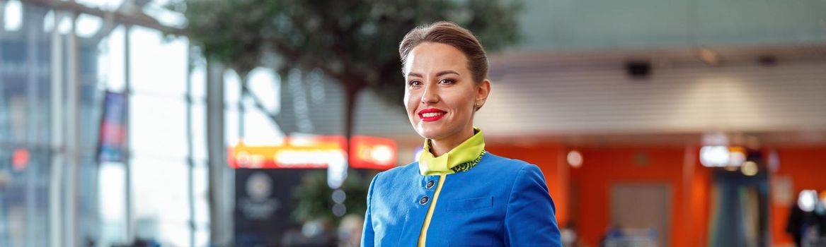 Joyful woman stewardess standing in airport terminal