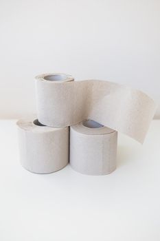 A couple of rolls of gray toilet paper are standing on a white table. Hygiene and cleanliness concept.