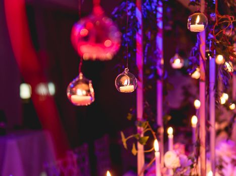 Candles in small glass circlular candle holders handled on strings. Beautiful decorations in purple electric light.