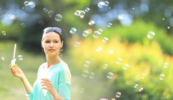 Young beautiful girl blowing bubbles outdoors