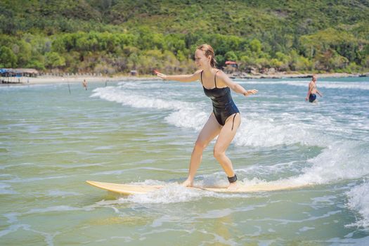 Coronavirus is over. Quarantine weakened. Take off the mask. Now you can go to public places. Beautiful young woman ride wave. Sporty surfer woman surfing on the background of blue sky, clouds and transparent waves. Outdoor Active