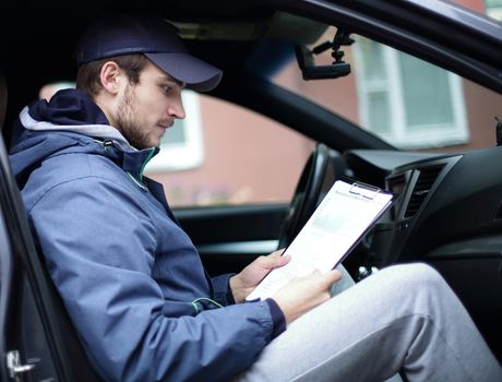 man with documents sitting in the car