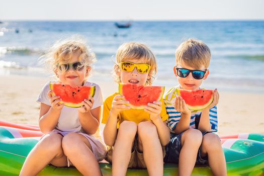 Coronavirus is over. Quarantine weakened. Take off the mask. Now you travel. Children eat watermelon on the beach in sunglasses