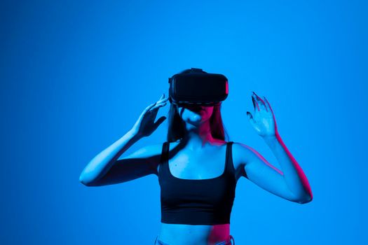 Young woman wearing VR goggles and interacts with cyberspace using swipe and stretching gestures while working on a project.