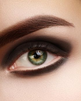 Beautiful macro photo of woman eye with black smoky makeup. Perfect shape eyebrows. Cosmetics and make-up