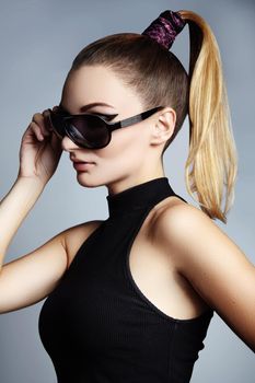 Beautiful young woman with black fashion sunglasses and glamour pinytail hairstyle. Eye wear style