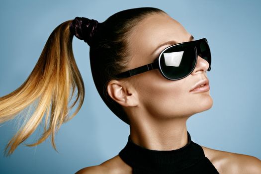 Beautiful young woman with black fashion sunglasses and glamour pinytail hairstyle. Eye wear style