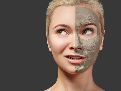 Beautiful Woman Applying Facial Mask. Beauty Treatments. Spa Girl Apply Clay Facial Mask on Grey Background. Funny Face