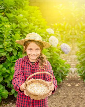 Farmer girl holding a basket of corn, portrait of farm girl with bird food, girl in the field feeding chickens and turkeys