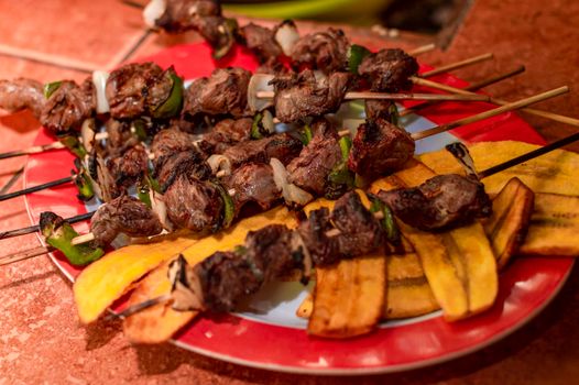 Roast beef skewers served on a silver, roast beef on skewers served with fried plantain