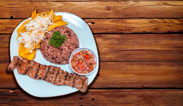 Roast beef with gallo pinto and pico de gallo, Nicaraguan food served on wooden table, Plate with roast beef and rice served on wooden table