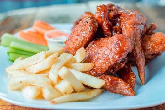 Close up of barbecue wings and french fries, plate of hot wings and french fries with copy space
