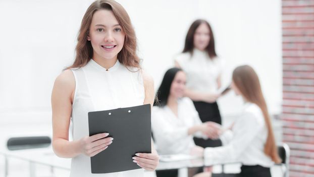 confident young business woman with clipboard on the background of business team
