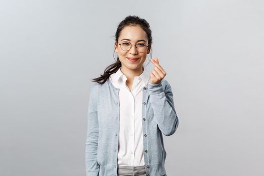 Emotions, people and lifestyle concept. Optimisic cute asian woman, young tutor in glasses entertain small kids during classes online education school, show korean heart sign and smile