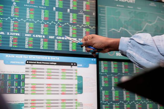 Close up shot of brokerage company employee indicating on display real time profit growth and market trend.
