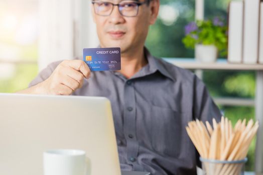senior adult man holding credit card and using technology on laptop computer