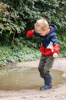 Toddler jumping in pool of water at the summer or autumn day.