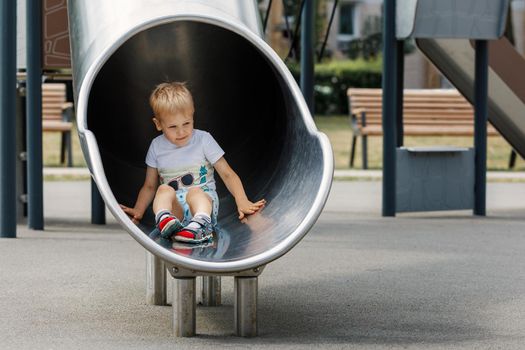 Happy child riding down slide on playground.
