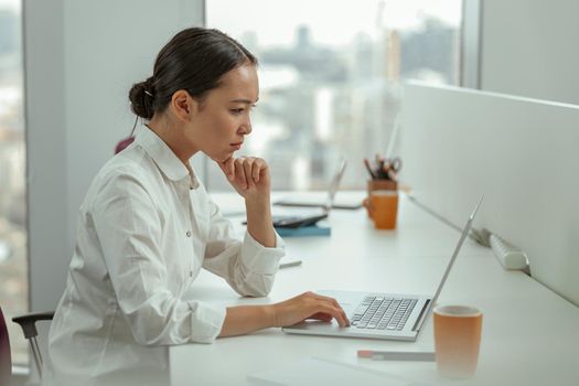 Focused asian business woman working laptop sitting in modern office