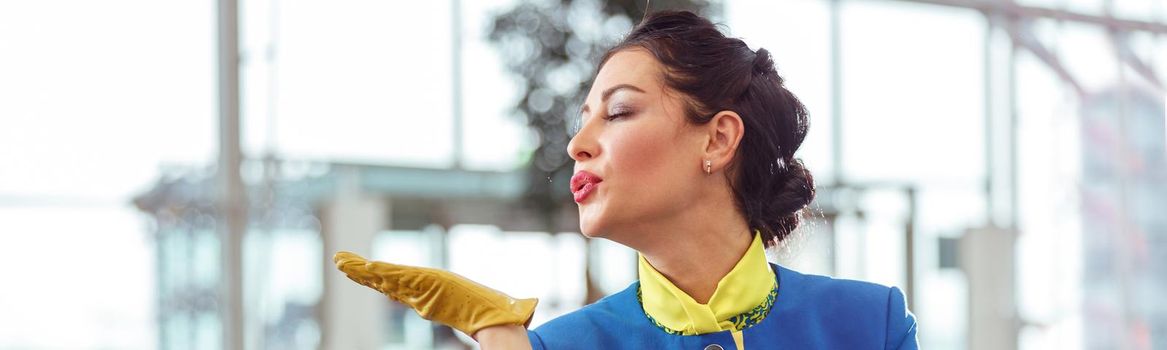 Female flight attendant blowing kiss at airport terminal