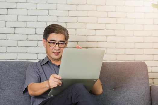 senior man with eyeglasses reading news on laptop
