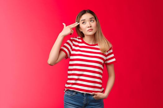 Upset blond asian girl wear striped t-shirt jeans dying boredom sighing look up hold finger gun pistol near temple commit suicide from boring meeting, attend uninteresting party red background