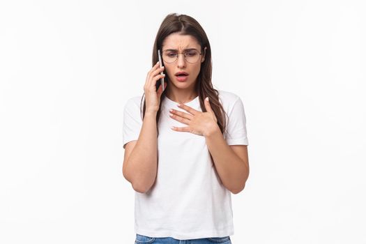 Communication, technology and lifestyle concept. Portrait of concerned and worried young woman express compassion and worry, calling sick friend asking if she okay, hold mobile near ear, touch heart