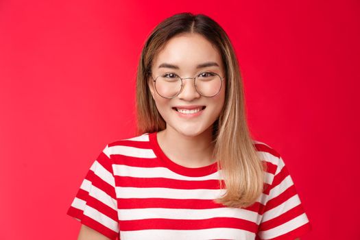 Close-up cheerful asian blond girl wear glasses smiling pleasant, give friendly toothy grin camera talking casually friends, standing happy show positive pleasant emotion, stand red background