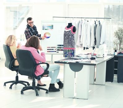 modern designer and his team choose the fabric for clothes in office