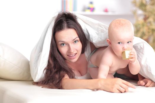 happy mother plays with the baby lying on the bed