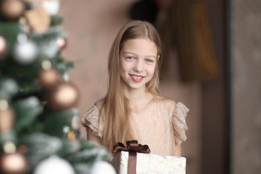 happy girl with Christmas gift standing near Christmas tree