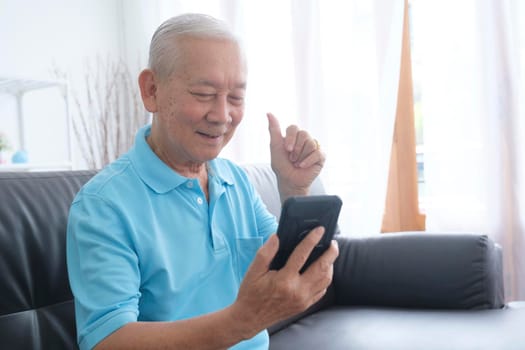 Elderly man making video call and waving at screen.