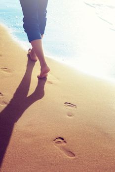 Walking on the beach, leaving footprints in the sand.