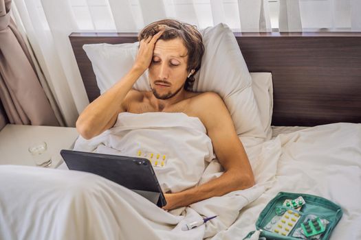 Male patient is sick while lying in his bed and calls an online doctor through a gadget