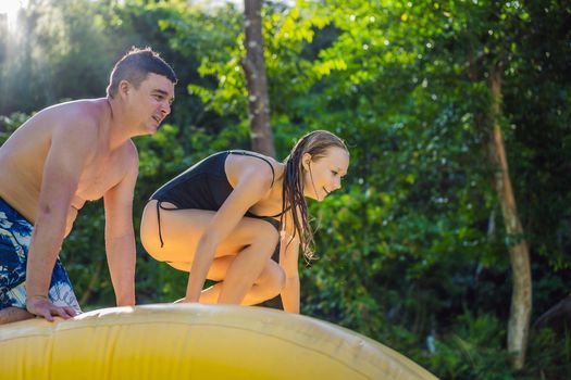 Woman and man go through an inflatable obstacle course in the pool