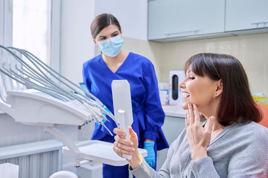 Dentist's office, woman patient looking at her teeth in the mirror