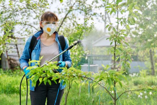 Woman with backpack garden spray gun under pressure handling pear fruit trees