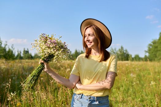 Summer portrait of happy 30s woman with bouquet of wildflowers