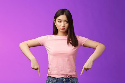 Serious-looking upset insecure asian female fighting stop cruel animal behaviour, pointing fingers down disappointed, look camera sincere fed up, standing depressed unsatisfied, purple background