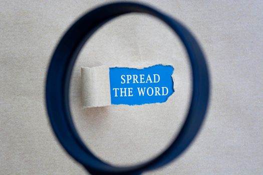 Spread the word text on torn paper with magnifying glass. Network concept.