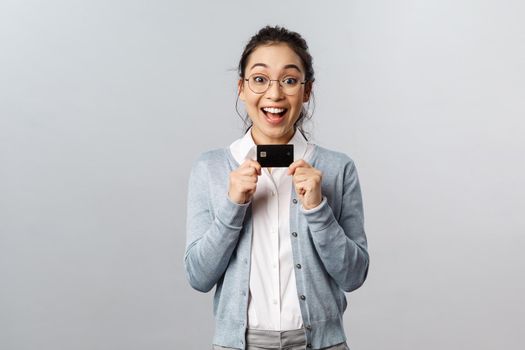 Technology, online purchases and finance concept. Excited happy asian woman in glasses, showing black credit card with smiling upbeat face, shopping in internet, pay for delivery