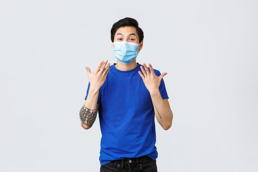 Different emotions, social distancing, self-quarantine on coronavirus and lifestyle concept. Happy and excited asian man in medical mask shaking hands, express cheer over good surprise news