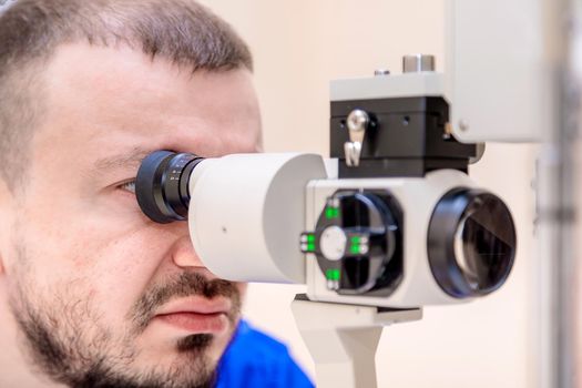 A male ophthalmologist checks a patient's vision with a modern device with a light beam