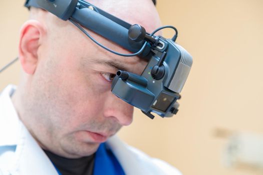 A male ophthalmologist checks a patient's vision with a binocular ophthalmoscope