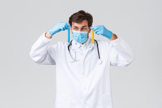 Hospital, healthcare workers, covid-19 treatment concept. Professional lab technician in white scrubs, medical mask and gloves, studying samples, searching vaccine, look ampoule