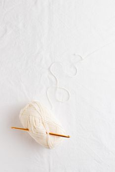 Crochet hook and ball of cotton yarn white color on a white table