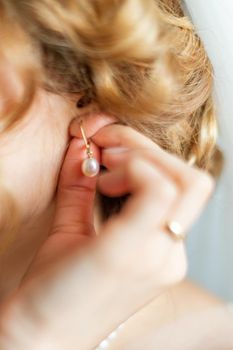 Bride dresses earrings before wedding
