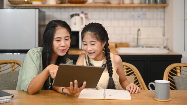 Caring asian mother helping her daughter doing homework. Concept of Virtual education, homeschooling