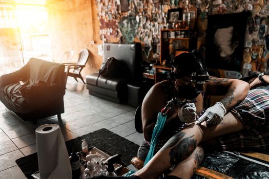 Latina tattoo artist working on an art on a client's leg in a studio in Nicaragua