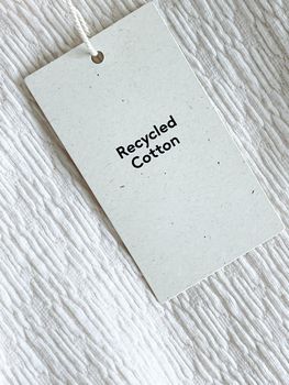 Recycled cotton fashion label tag, sale price card on luxury fabric background, shopping and retail